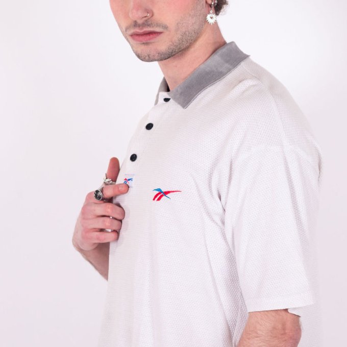 Polo Reebok vintage blanc texturé avec logo brodé rouge et bleu, col gris contrastant, coupe oversize et tissu épais - profil