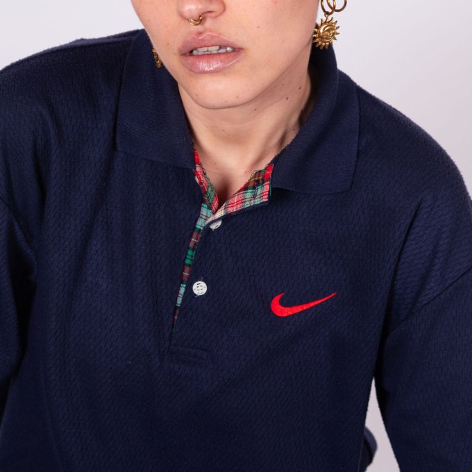 Polo vintage Nike bleu marine en coton épais, swoosh brodé rouge, doublure tartan écossais et coupe années 90 - détail logo avant