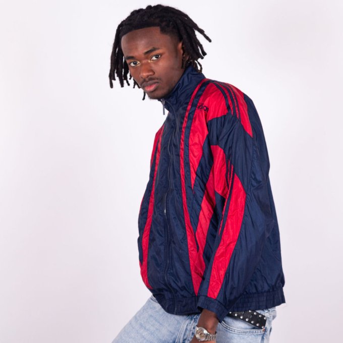 Veste Adidas vintage bleu marine avec bandes rouges sur les manches, coupe droite, col montant zippé, logo brodé sur la poitrine, style sportswear des années 90