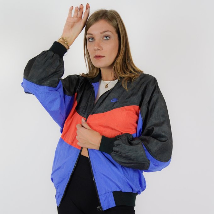 Veste vintage Nike International orange, bleu et noir avec logo brodé au dos.