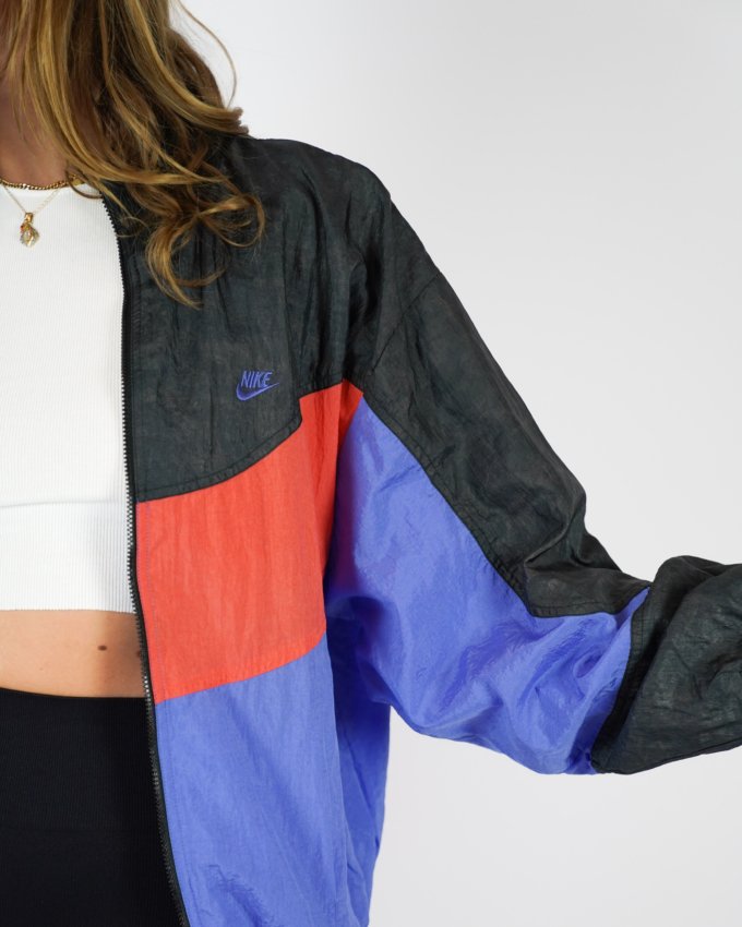 Veste vintage Nike International orange, bleu et noir avec logo brodé au dos.