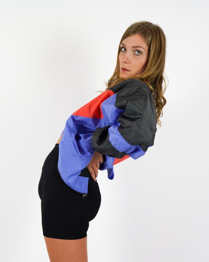 Veste vintage Nike International orange, bleu et noir avec logo brodé au dos.